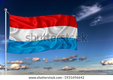 Luxembourg national flag waving in the wind against deep blue sky.  International relations concept.