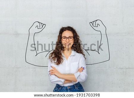 Happy young business woman posing isolated shows muscle Royalty-Free Stock Photo #1931703398