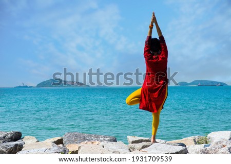 woman practices yoga. Girl doing yoga on the grass by the sea. Side view picture of  woman on the beach with yoga  Pose