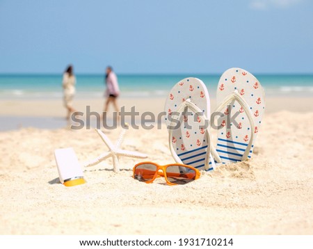Summer assessories. Planing to travel with sunblock and sandal on the beatiful beach and blue sky background. Tropical fashion. Summer Fashion on holiday concept. 