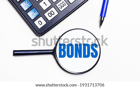 On a light background, a black calculator, a blue pen and a magnifying glass with tex inside the BONDS. View from above