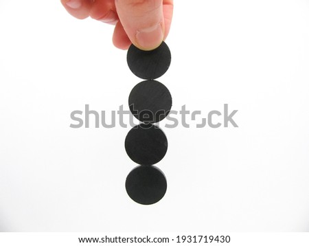 four round little gray magnets hang by a chain in his hand