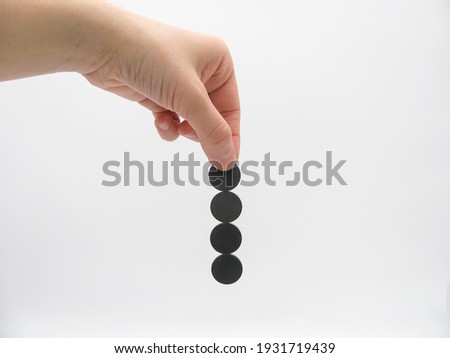 four round little gray magnets hang by a chain in his hand