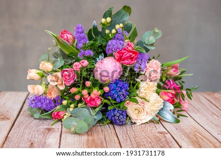 Close up view of a beautiful bouquet of mixed coloful flowers on wooden table. The concept of a flower shop and flower delivery as a family business, florist work. Royalty-Free Stock Photo #1931731178