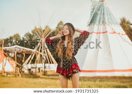 Young girl beautiful tourist talking on the phone, video communication roaming on the background teepee, tipi- native indian house. Unusual places to stay