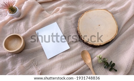 container, with Wooden cutting board, white card, flowers on a fabric background, packaging mockup with empty space to display your branding design.