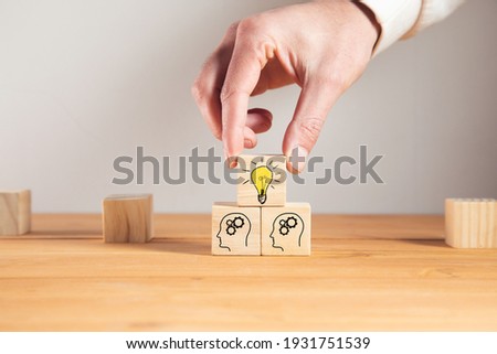 Concept creative idea and innovation. Hand picked wooden cube block with head human symbol and light bulb icon Royalty-Free Stock Photo #1931751539