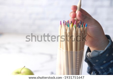 Close up of a child hand picking colored pencil with copy space 