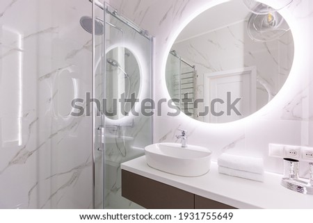 Interior photo of a modern bathroom with shower, decorated with white stylish marble tiles