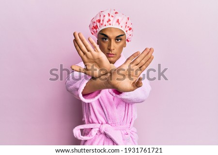 Hispanic man wearing make up wearing shower towel cap and bathrobe rejection expression crossing arms doing negative sign, angry face 