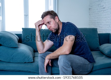 Unhappy depressed caucasian male crying in living room couch feeling desperate and lonely isolated at home. In stressed from work, unemployment, anxiety, heartbroken and depression concept Royalty-Free Stock Photo #1931768105