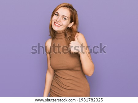 Young caucasian woman wearing casual clothes doing happy thumbs up gesture with hand. approving expression looking at the camera showing success. 