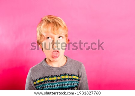 Young child boy making strange faces, rolling his eyes in a grotesque way.