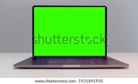Close up of a new laptop computer with chroma key monitor. Action. Opened laptop with green screen isolated on white wall background.