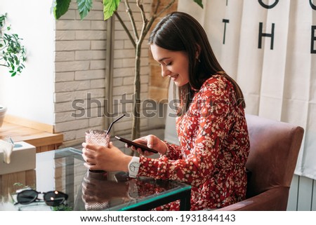 Online dating, Love at distance. Woman in cafe using dating app and swiping user photos. Young woman using mobile phone, reading text message and communicates in messenger with boyfriend.
