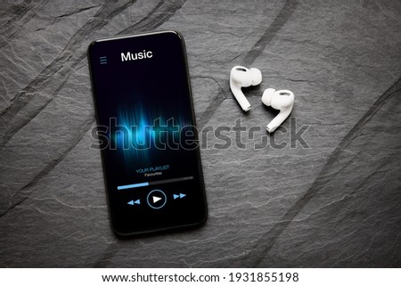 Music player on mobile phone and wireless earbuds Royalty-Free Stock Photo #1931855198