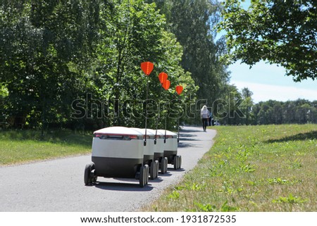moving delivery robots on the street. crossing the road with a pedestrians. Cyber-couriers are cruising the sidewalks in Estonia. Copy space for design. Modern delivery concept-robots delivery Royalty-Free Stock Photo #1931872535