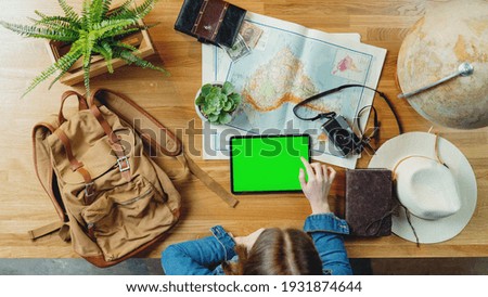 Top view of young woman with tablet and maps planning vacation trip holiday, desktop travel chroma key concept.