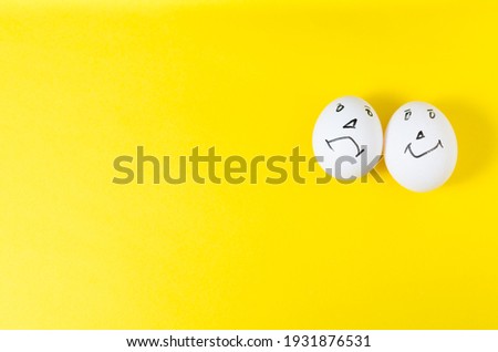 one egg with a smiley funny, the second sad. There is an empty space for text, Two chicken eggs in the form of emoticons