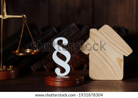 Wooden house and paragraph figure and scales. Standardization and construction of housing. Real estate legal services