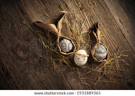 Easter eggs, festive card, Stylish packaged monochrome eggs lying on wooden backdrop with hay. Ecofriendly holiday