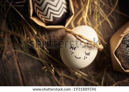 Cute Easter Egg angel lying on wooden surface with hay, close up. Christian religious holiday