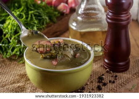 green broth with pepperoni and cabbage top view on rustic wooden table with selective focus and golden spoon 
