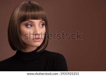 Portrait of a beautiful brown-haired woman with a short haircut on a brown background Royalty-Free Stock Photo #1931925251