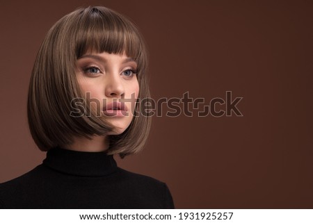 Portrait of a beautiful brown-haired woman with a short haircut on a brown background Royalty-Free Stock Photo #1931925257