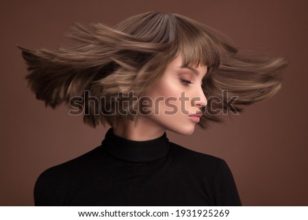 Portrait of a beautiful brown-haired woman with a short haircut on a brown background Royalty-Free Stock Photo #1931925269