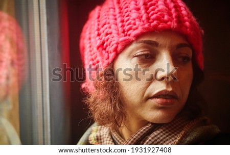 close up winter portrait of a happy and beautiful young lady in a pink knitted beanie hat
