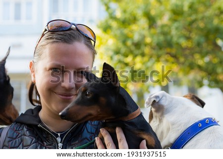 A young woman enjoys companionship with her beloved pinscher dog in a city park. Selective focus with blurred background. Shallow depth of field.