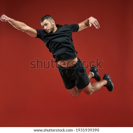 Strong athlete jumping up in the indoors while posing at the photo camera
