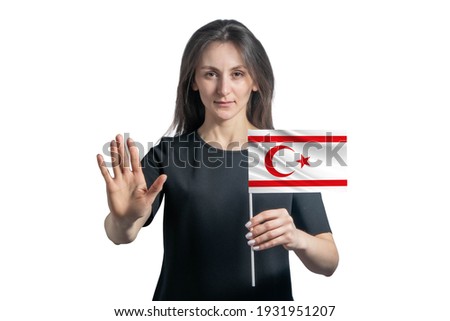 Happy young white woman holding flag of Turkish Republic of Northern Cyprus and with a serious face shows a hand stop sign isolated on a white background.