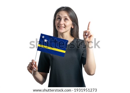 Happy young white woman holding flag of Curacao and points thumbs up isolated on a white background.