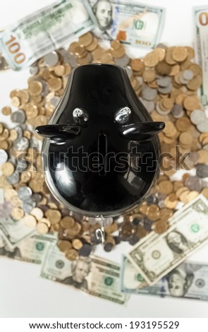 Closeup photo of black piggy bank on pile of coins