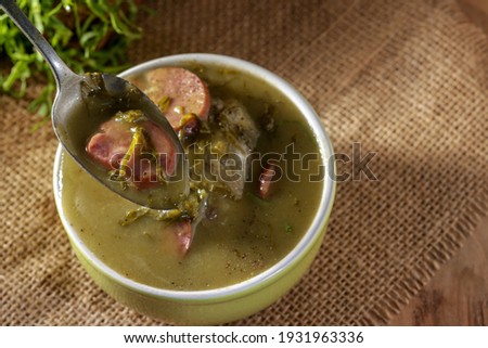 green broth with pepperoni and cabbage top view on rustic wooden table with selective focus with broth on spoon
