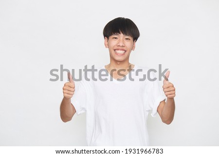 Asian young man wearing a T-shirt going thumb up on white background.