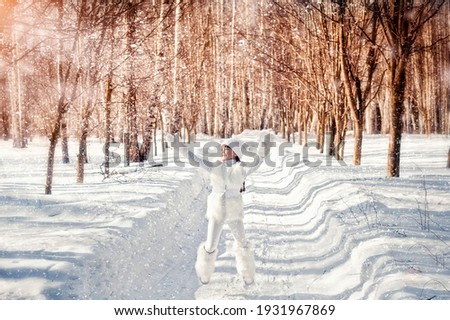 Winter portrait of a girl in the park.
A beautiful little girl stands in white clothes against the background of a winter forest.