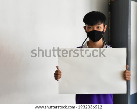 Single Asian boy holding blank paper in hands, concept for protesting human events in each situation around the world. Soft and selective focus.