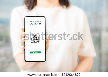 Woman holding smart phone with Covid-19 health pass. Coronavirus vaccinations certified app interface concept with qr code on smart phone in woman hand. Covid-19 Health Passport concept. Royalty-Free Stock Photo #1932064877