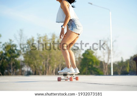 Close-up Asian women surf skate or skates board outdoors on beautiful summer day. Happy young women play surf skate at park on morning time. Royalty-Free Stock Photo #1932073181
