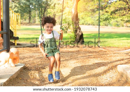 Happy little african american boy on a swing in the park.