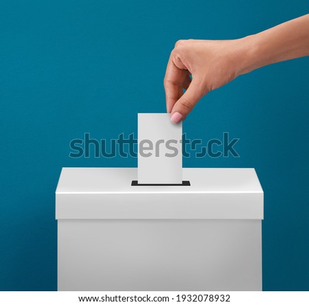 female or women Voter Holds Envelope In her  Hand Above Vote Ballot for casting vote on blue background Royalty-Free Stock Photo #1932078932
