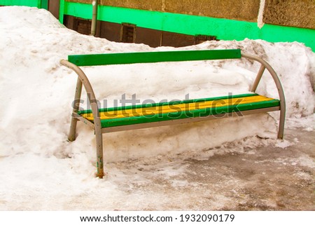 bench near the house and snow on the street 