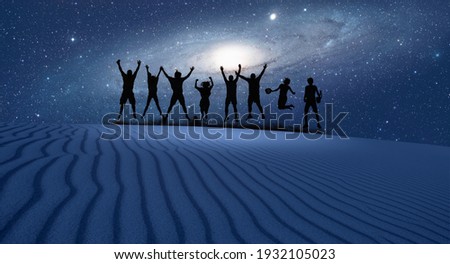 Silhouette of friends jumping on the sand dune, Andromeda Galaxy in the background "Elements of this image furnished by NASA "