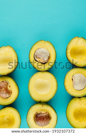Delicous cut ripe avocados with and without cores on light blue background