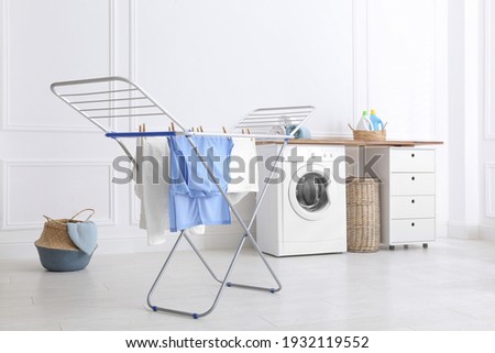 Clean laundry hanging on drying rack indoors Royalty-Free Stock Photo #1932119552