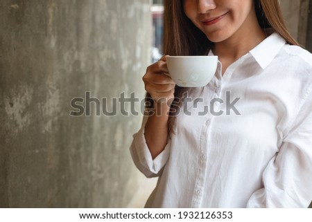 Closeup image of a beautiful young asian woman smelling and drinking coffee in cafe
