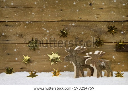 Two wooden handmade reindeer on a background with golden stars and snow.